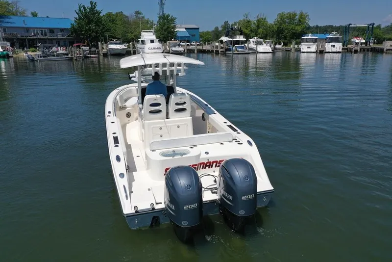 Slide: The Image of 2023 Cobia 280 Center Console boat with twin Yamaha engines on a calm lake. - 21