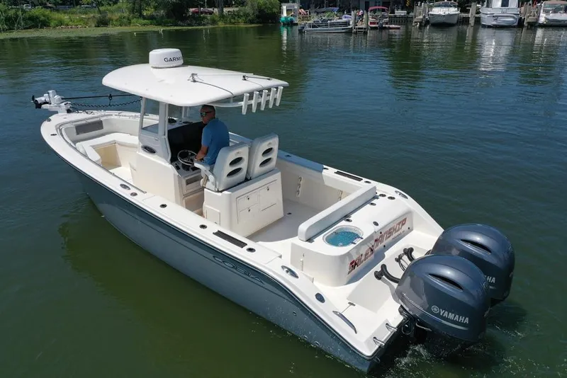 Slide: The Image of 2023 Cobia 280 Center Console boat with dual Yamaha engines on calm water. - 23