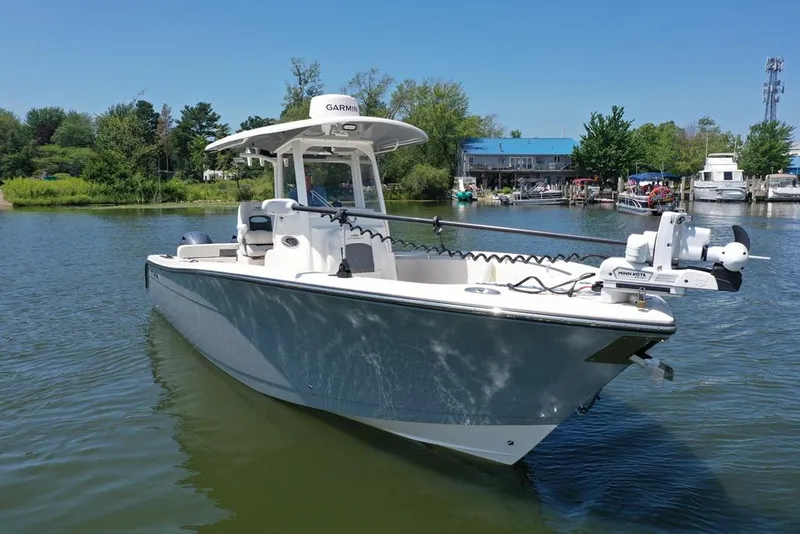 Slide: The Image of 2023 Cobia 280 Center Console boat on calm water, surrounded by greenery and docks. - 31