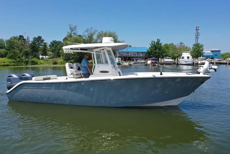 Slide: The Image of 2023 Cobia 280 Center Console boat on calm water, featuring dual outboard engines. - 38