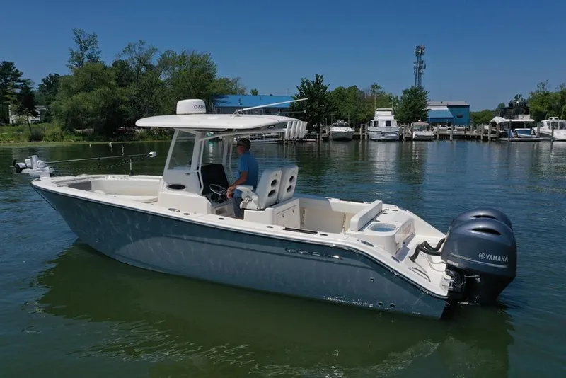 Slide: The Image of 2023 Cobia 280 Center Console boat on calm water with Yamaha engines. - 47