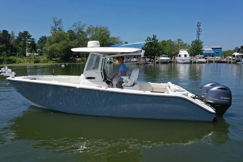 Slide: The Image of 2023 Cobia 280 Center Console boat on calm water, featuring dual Yamaha engines. - 48