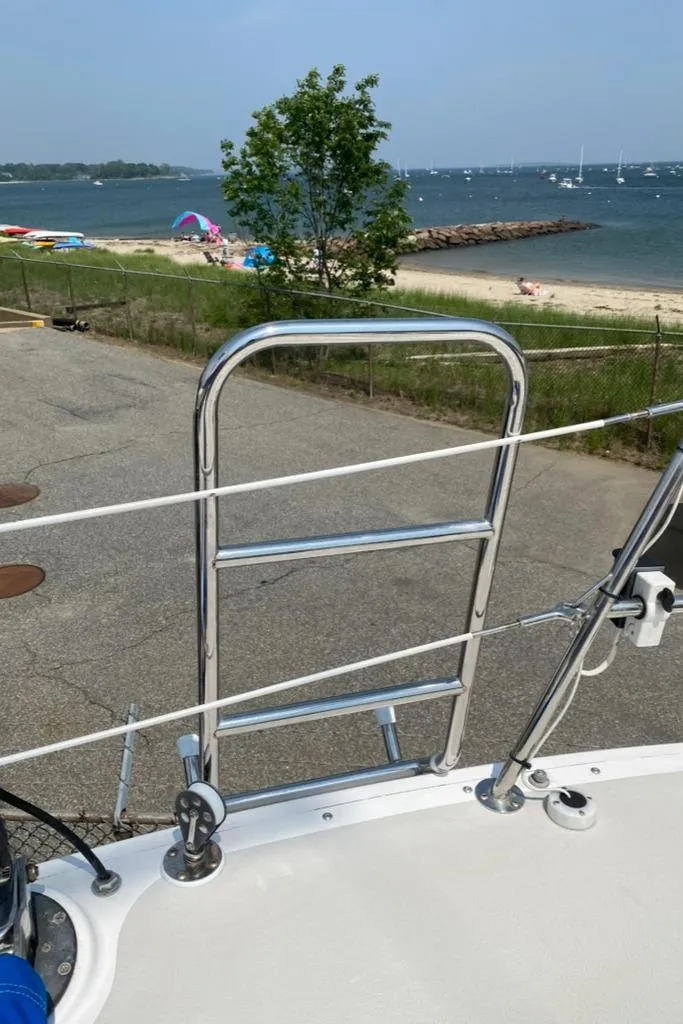 Slide: The Image of Sailboat deck view with ladder, overlooking a beach and ocean. Express 37, 1986 model. - 14