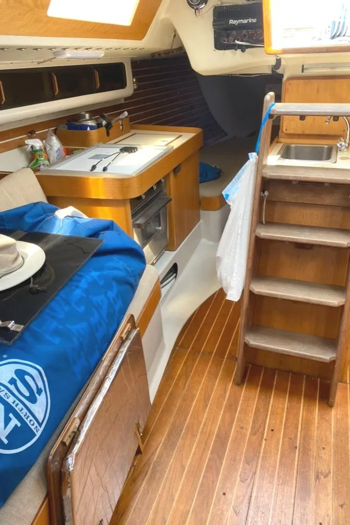 Slide: The Image of Interior of 1986 Express 37 sailboat with wooden flooring and compact kitchen area. - 37