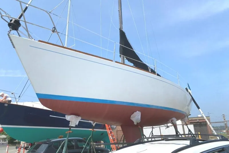Slide: The Image of 1986 Express 37 sailboat on dry dock, white hull with blue stripe, clear sky background. - 5