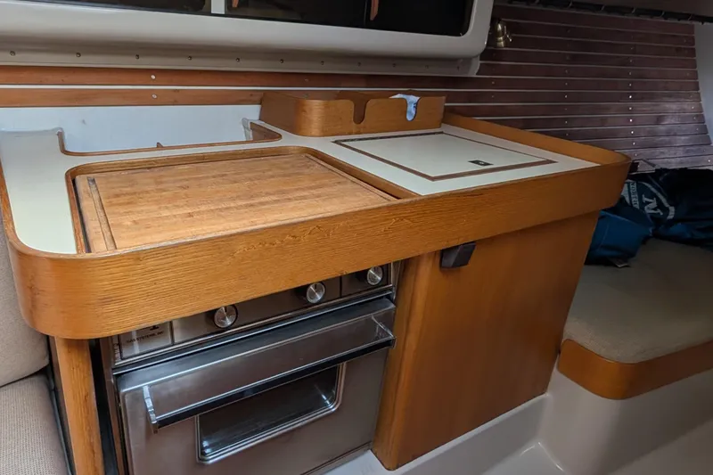 Slide: The Image of Compact kitchen area in a 1986 Express 37 sailboat with wooden cabinetry and stove. - 50