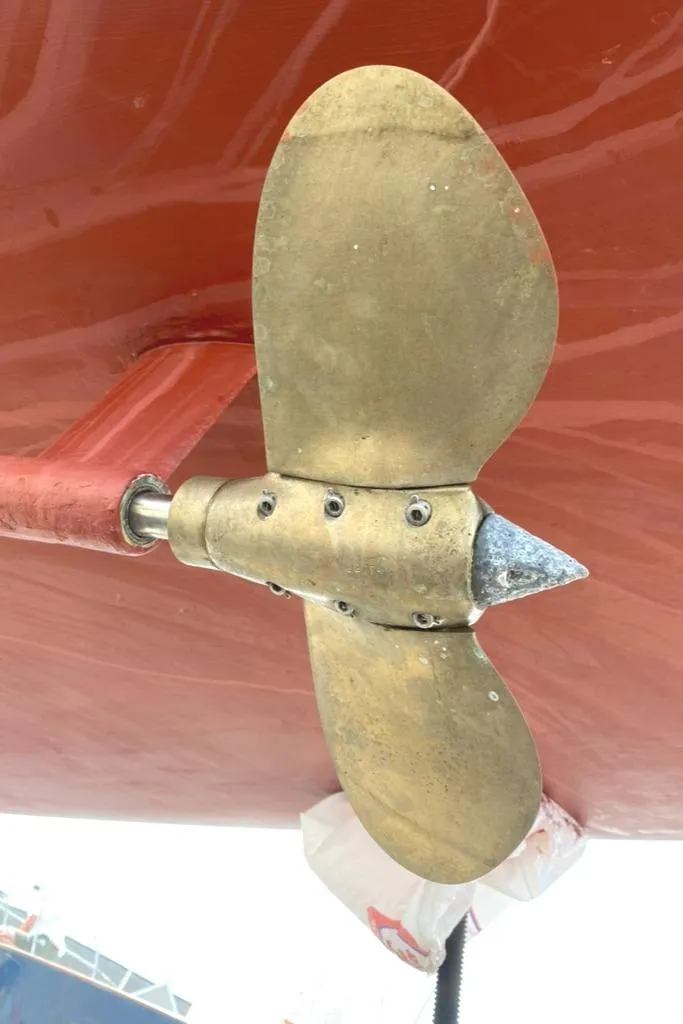 Slide: The Image of Brass propeller of 1986 Express 37 sailboat against red hull background. - 8