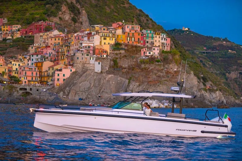 Slide: The Image of 2025 Axopar 37 Sun Top boat cruising near colorful coastal village. - 4