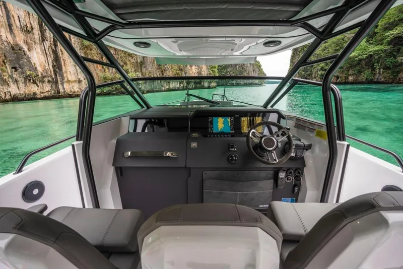 Slide: The Image of 2025 Axopar 37 Sun Top boat interior with scenic turquoise water and cliffs. - 6