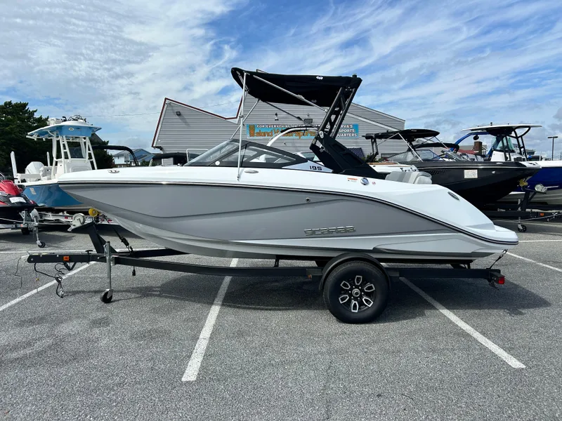 The Image of 2025 Scarab 195 SE boat on trailer, parked in a lot under a cloudy sky. - 1