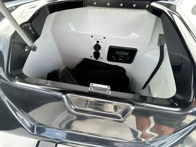 Slide: The Image of Open storage compartment in 2025 Scarab 195 SE boat, featuring power outlets and control panel. - 15