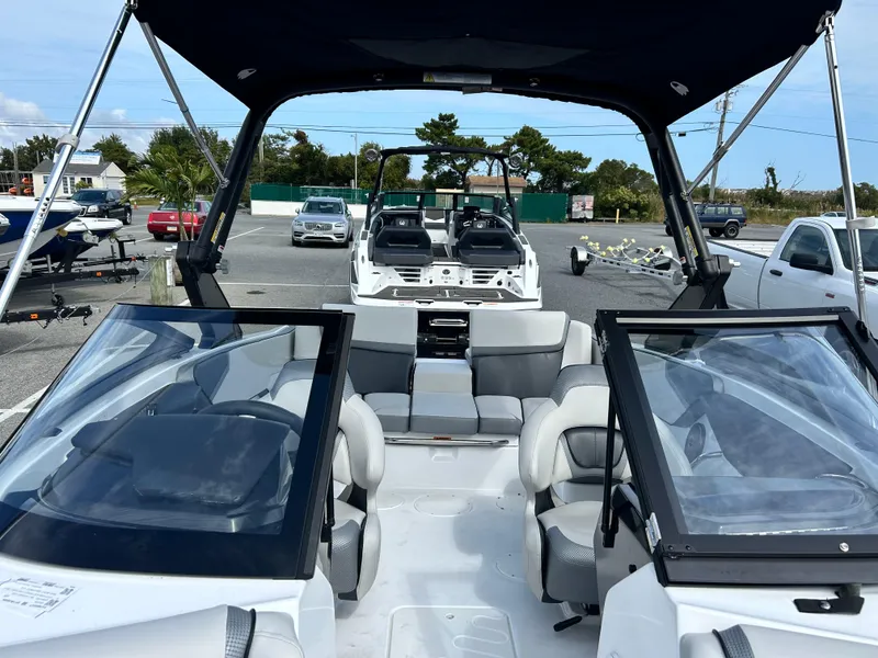 Slide: The Image of 2025 Scarab 195 SE boat with sleek interior and dual windshields, parked outdoors. - 7