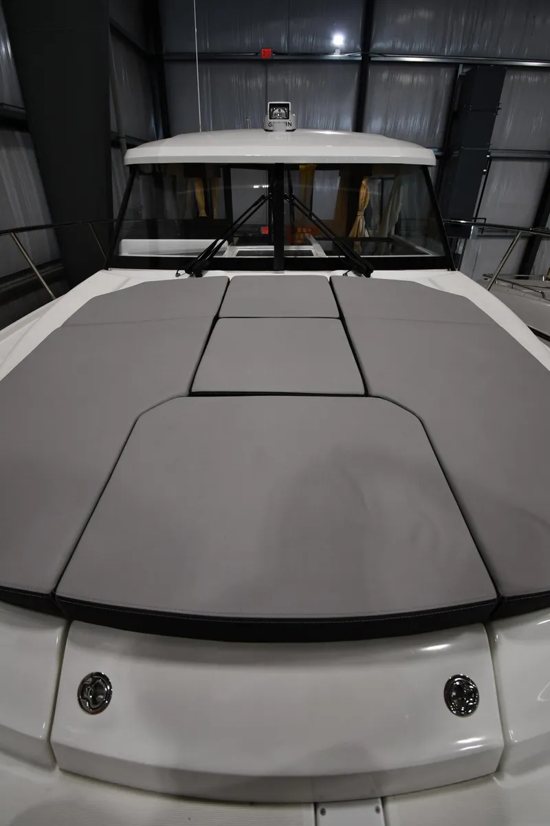 Slide: The Image of 2023 Jeanneau NC1095 boat with cushioned deck in a showroom. - 16