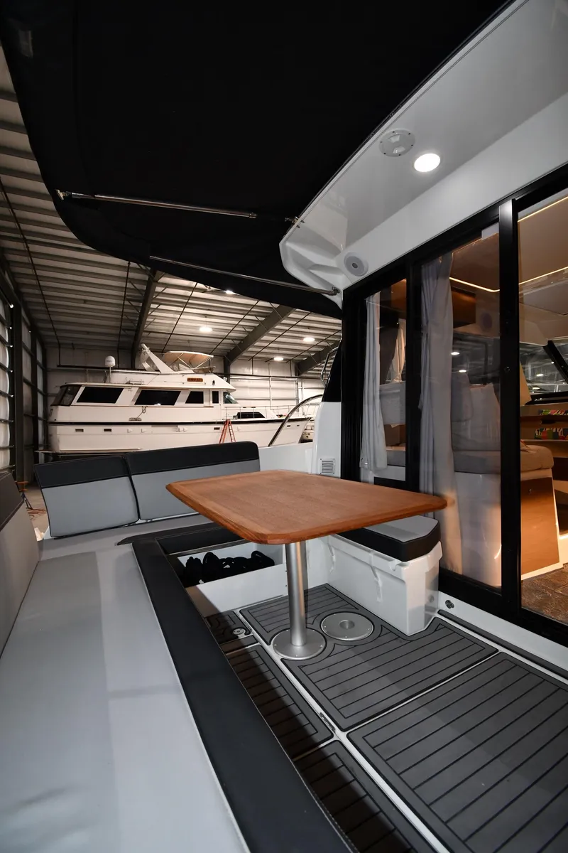 Slide: The Image of 2023 Jeanneau NC1095 yacht interior with seating and table in a marina setting. - 23