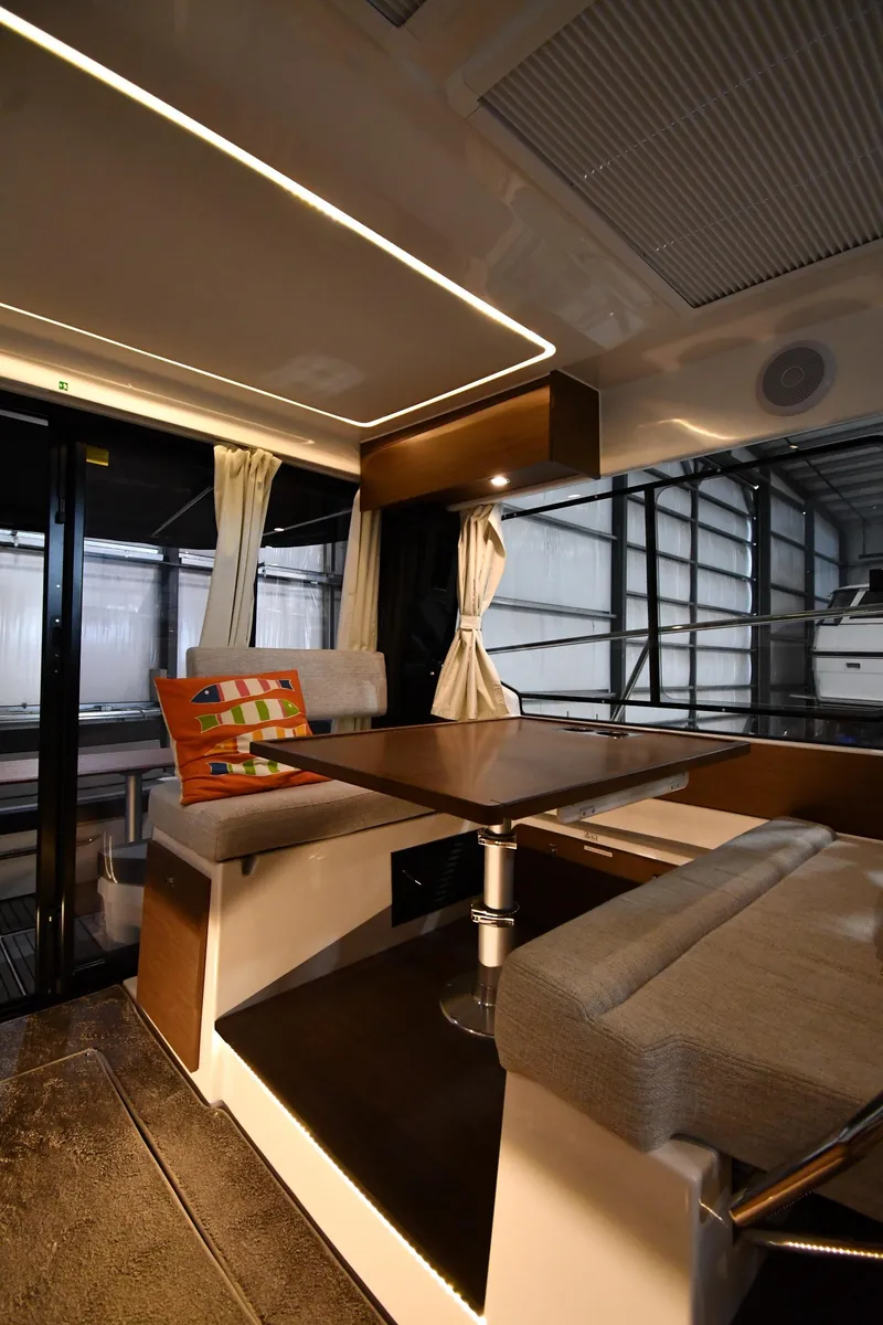 Slide: The Image of 2023 Jeanneau NC1095 interior with modern seating, table, and decorative pillow. - 41