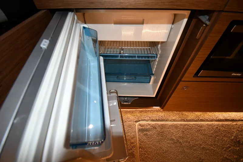 Slide: The Image of Interior view of a 2023 Jeanneau NC1095 boat refrigerator, showcasing storage compartments. - 47