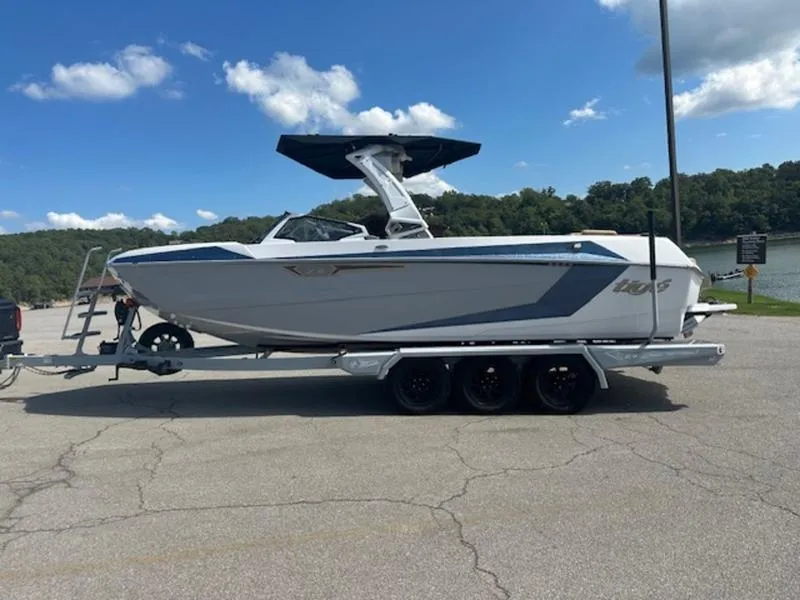 The Image of 2025 Tigé Ultré 25ZX boat on trailer, parked near a lake under a clear blue sky. - 0