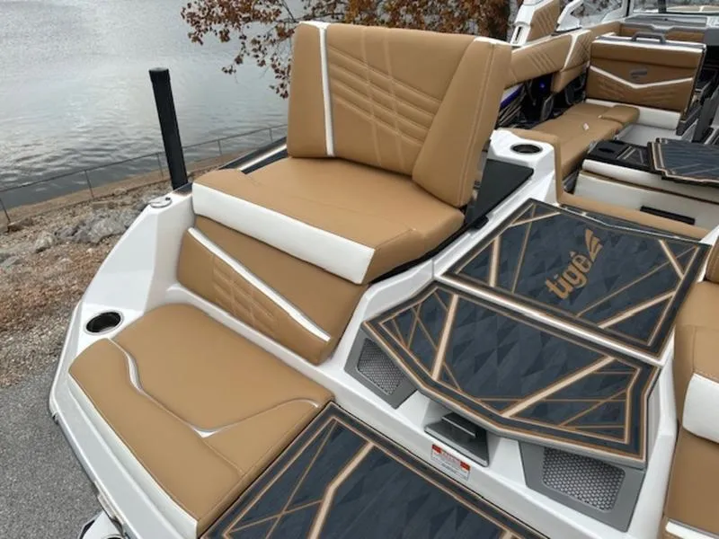 Slide: The Image of 2025 Tigé Ultré 25ZX boat interior with tan and white seating, near a lake. - 12