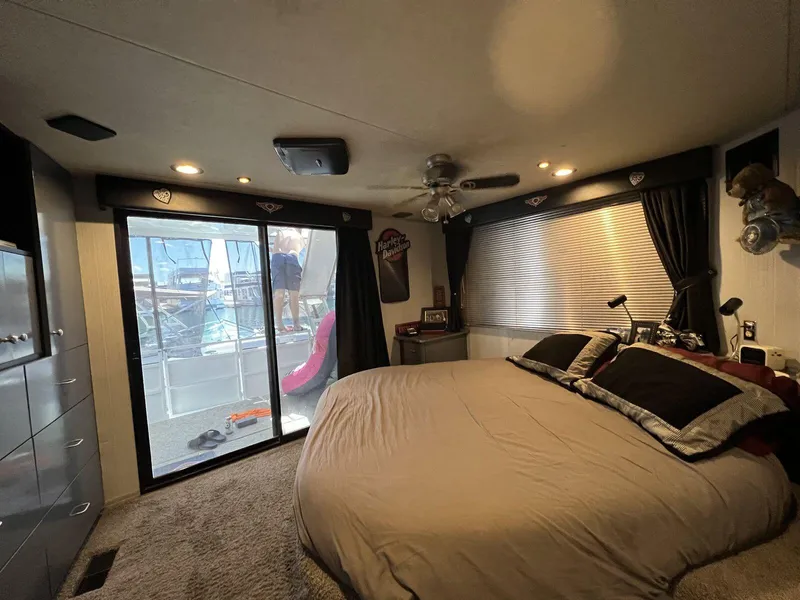Slide: The Image of Cozy bedroom in a 1996 Skipperliner 61x16 houseboat with large bed and sliding glass door. - 12