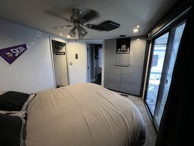 Slide: The Image of Bedroom interior of 1996 Skipperliner 61x16 Houseboat with bed, storage, and sliding glass door. - 14