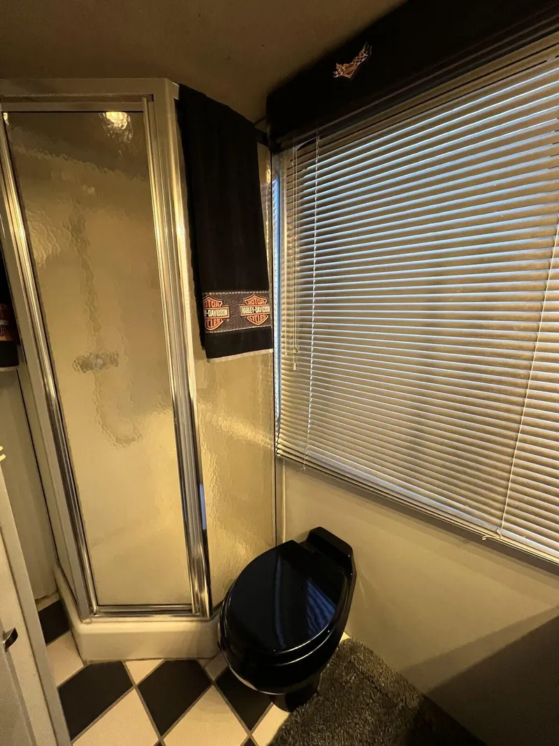Slide: The Image of 1996 Skipperliner 61x16 Houseboat bathroom with shower, black toilet, and window blinds. - 18