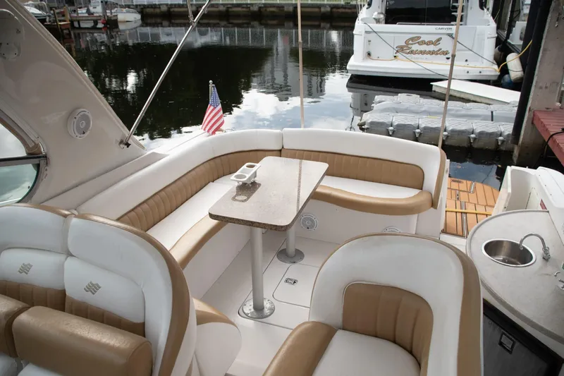 Slide: The Image of 2005 Four Winns 378 Vista boat interior with seating, table, and American flag at dock. - 11