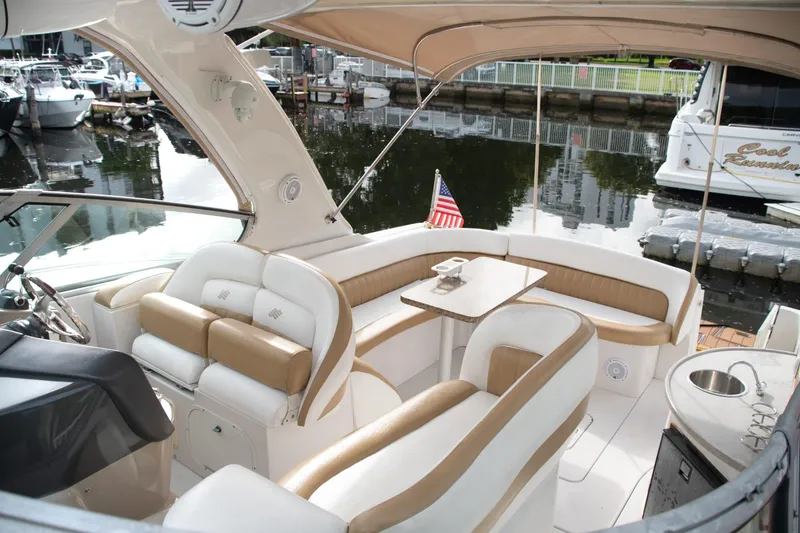 Slide: The Image of 2005 Four Winns 378 Vista yacht interior with seating, table, and American flag at marina. - 12