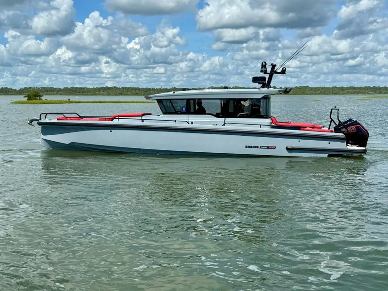 Slide: The Image of 2023 Axopar Shadow 900XC boat on calm water under a cloudy sky. - 1
