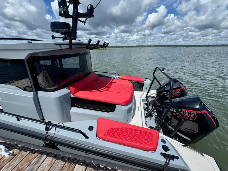 Slide: The Image of 2023 Axopar Shadow 900XC boat with red seating, twin engines, on a calm lake. - 12