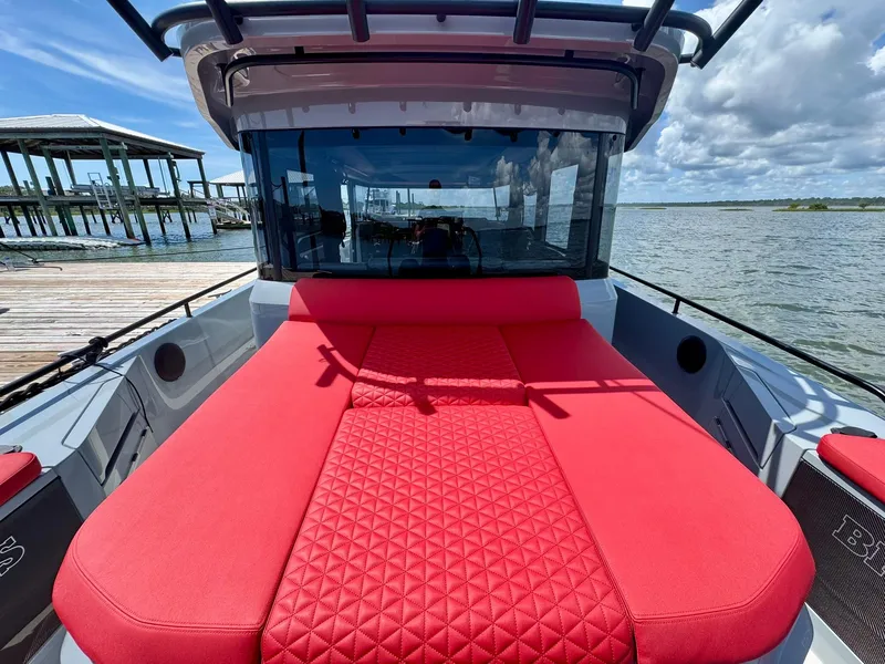 Slide: The Image of 2023 Axopar Shadow 900XC with red seating, docked by a scenic waterfront. - 13