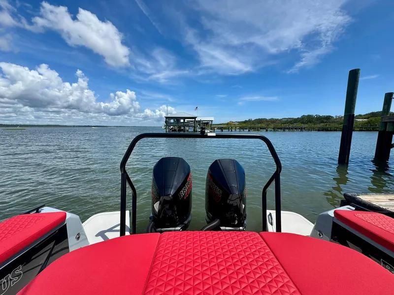 Slide: The Image of 2023 Axopar Shadow 900XC boat with red seating, dual engines, and scenic water view. - 16