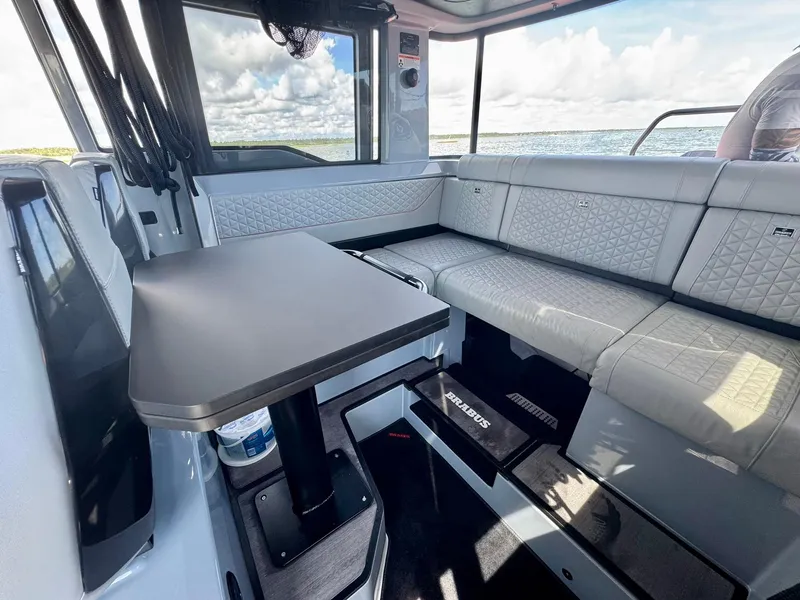 Slide: The Image of 2023 Axopar Shadow 900XC interior with modern seating and table, overlooking the ocean. - 27