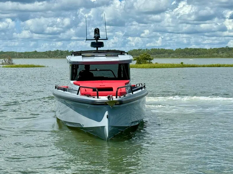 Slide: The Image of 2023 Axopar Shadow 900XC boat cruising on a scenic waterway under a cloudy sky. - 3