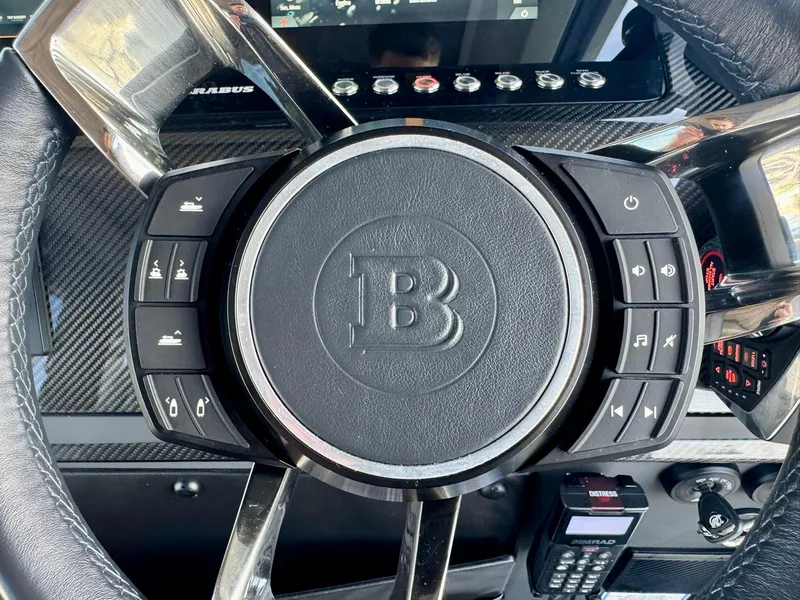 Slide: The Image of Steering wheel of 2023 Axopar Shadow 900XC with control buttons and carbon fiber accents. - 35