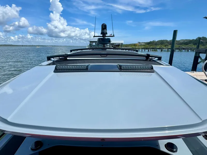 Slide: The Image of 2023 Axopar Shadow 900XC boat docked by the water under a clear blue sky. - 48