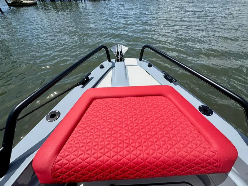 Slide: The Image of 2023 Axopar Shadow 900XC boat with red cushioned seating on the bow, docked on water. - 9