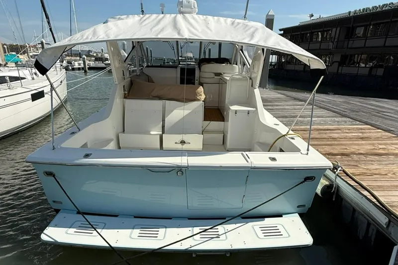 Slide: The Image of 1996 Hatteras 39 Sport Express docked, rear view with canopy and seating area. - 4