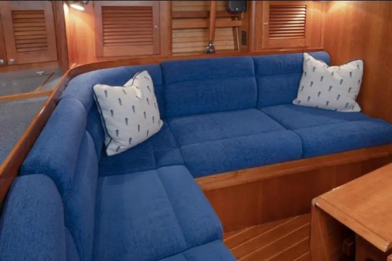 Slide: The Image of Cozy blue seating area in 2000 Sabre 402 yacht interior with nautical-themed pillows. - 2
