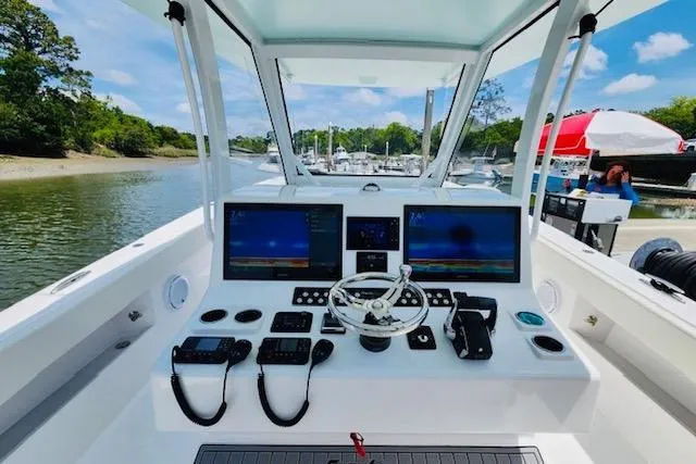 Slide: The Image of 2024 Front Runner 37 Catamaran helm with dual screens and controls, docked by a scenic river. - 4