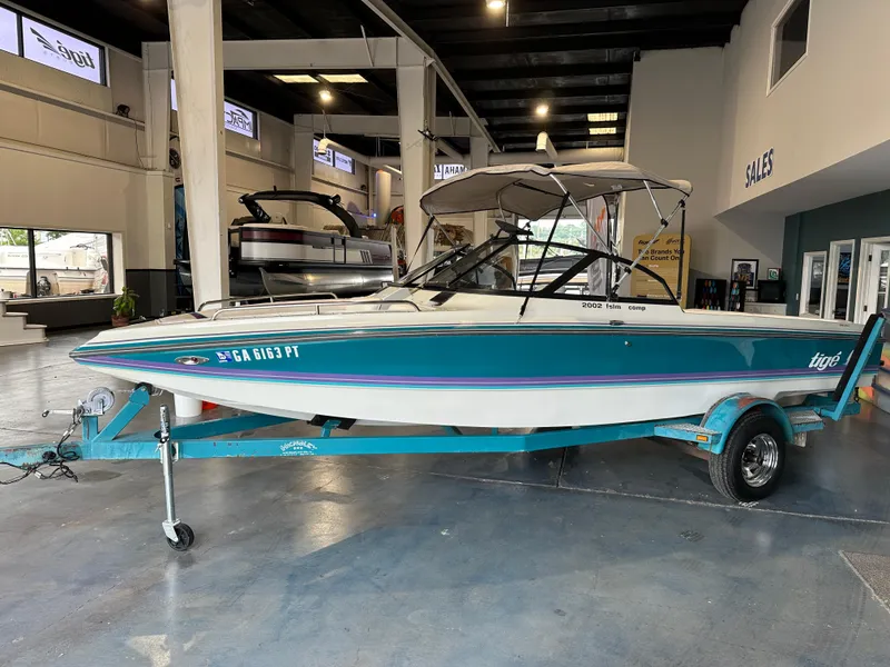The Image of 1995 Tigé 2002 FSLM COMP boat displayed indoors on a trailer. - 1