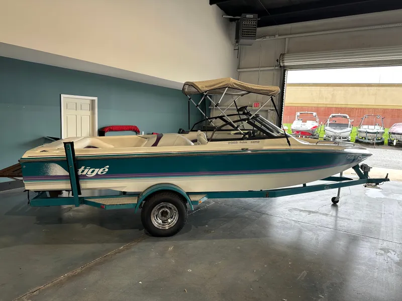 Slide: The Image of 1995 Tigé 2002 FSLM COMP boat in indoor showroom, teal and white design. - 2