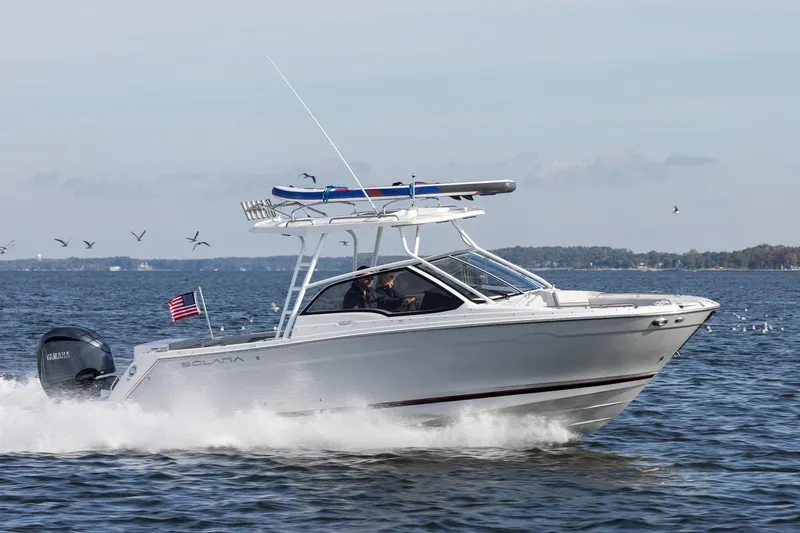 Slide: The Image of 2026 Solara S-250 DC boat cruising on open water with American flag. - 2
