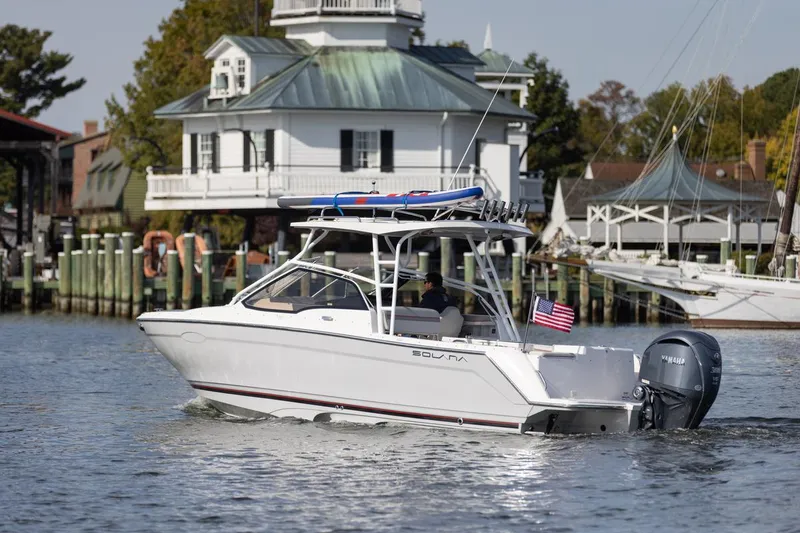 Slide: The Image of 2026 Solara S-250 DC boat cruising near a waterfront house with American flag. - 3