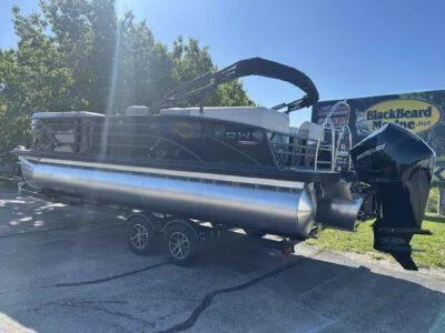 Slide: The Image of 2025 Lowe SS 230 pontoon boat on trailer, parked outdoors in sunny weather. - 2