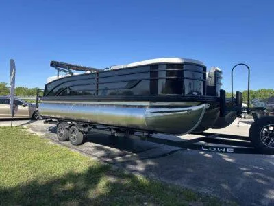 Slide: The Image of 2025 Lowe SS 230 pontoon boat on trailer, parked outdoors under clear blue sky. - 5