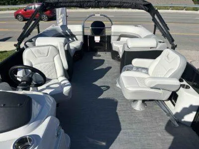 Slide: The Image of 2025 Lowe SS 230 boat interior with white seating and steering wheel, parked near a road. - 9