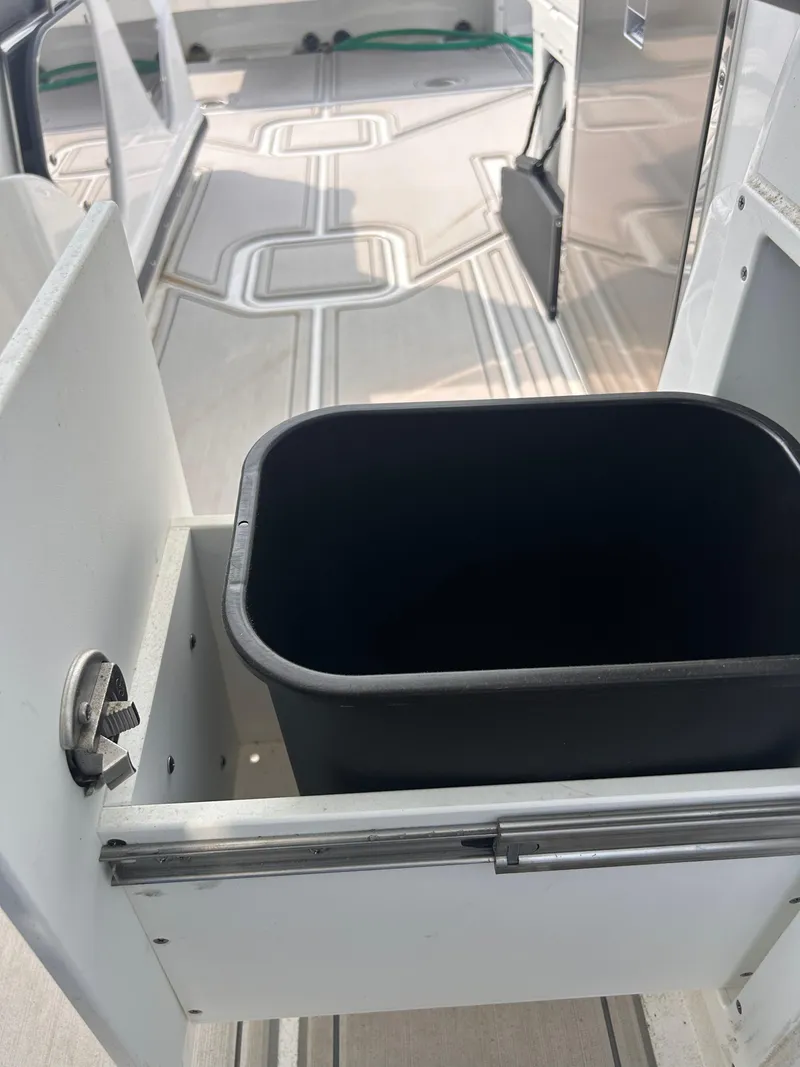 Slide: The Image of 2024 Blackfin 302DC boat interior with built-in storage compartment and trash bin. - 13