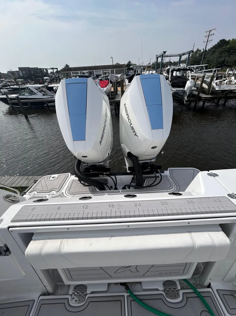 Slide: The Image of 2024 Blackfin 302DC boat with dual Mercury outboard engines at a marina. - 15