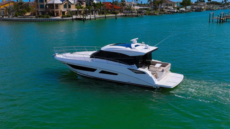 Slide: The Image of 2016 Sea Ray 470 Sundancer yacht cruising in clear blue waters near luxury waterfront homes. - 3
