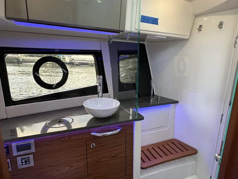 Slide: The Image of Interior of 2022 Boston Whaler 405 Conquest, featuring modern bathroom with sink and window. - 13